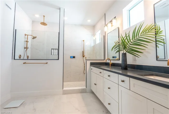 Spacious bathroom featuring a dual vanity with dark countertops and white cabinetry