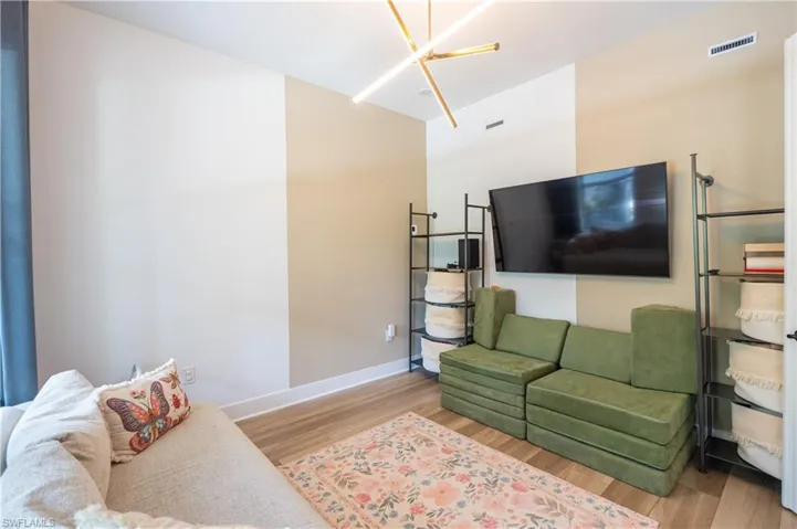 Contemporary interior space featuring wood-finish flooring, a modern linear light fixture, and a wall-mounted television