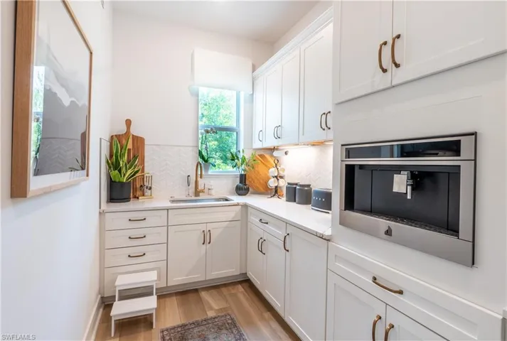 Prep kitchen featuring white shaker cabinetry, an integrated coffee system, light countertops, and wood-finish flooring