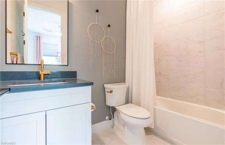 Ensuite Modern bathroom featuring a white vanity with a dark countertop and gold-finish faucet