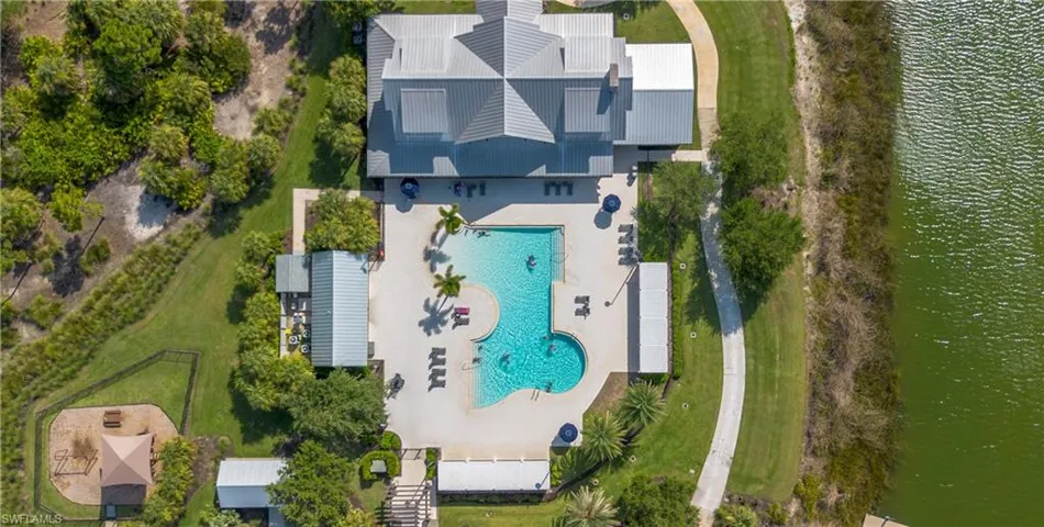 Outdoor recreation area featuring a resort-style swimming pool, surrounding lounge areas, a playground, and extensive green spaces just a few short minute walk