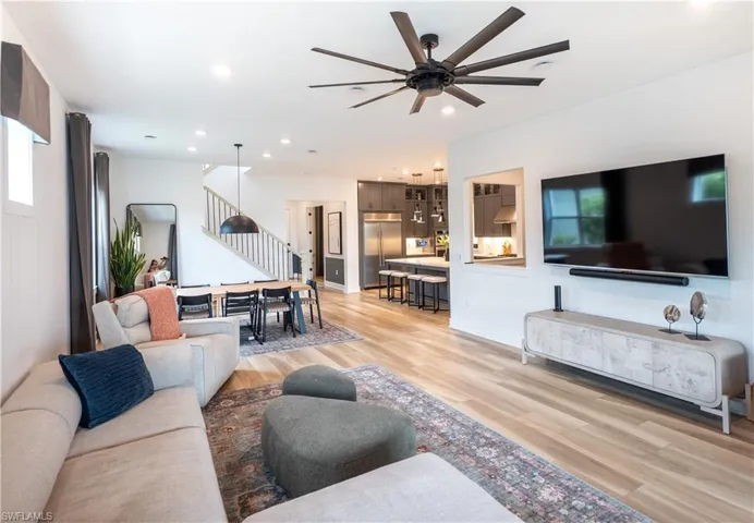 Open-concept living space featuring wood-finish flooring and a contemporary multi-blade ceiling fan