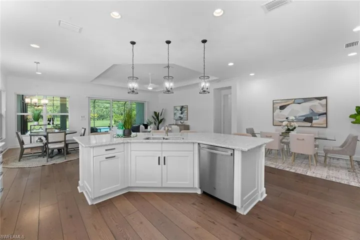 Kitchen with sink, dark hardwood / wood-style floors, an island with sink, dishwasher, and a raised ceiling
