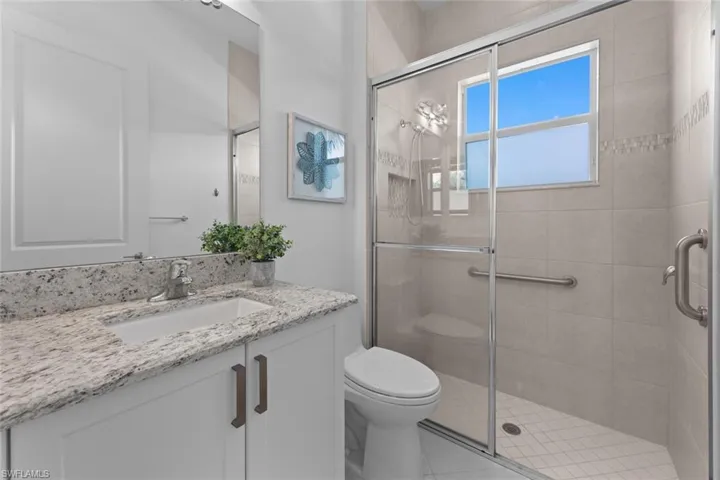Second guest Bathroom featuring tile patterned floors, vanity, a shower with door, and toilet