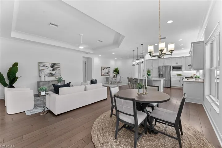 Dining room with an inviting chandelier, ornamental molding, a tray ceiling, and hardwood / wood-style floors