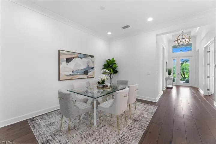 Dining area featuring dark hardwood / wood-style floors, a notable chandelier, french doors, and ornamental molding