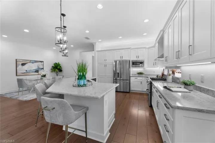 Kitchen featuring hanging light fixtures, crown molding, dark hardwood / wood-style floors, a kitchen island, and appliances with stainless steel finishes