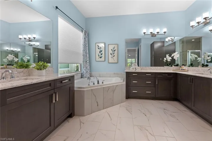 Bathroom featuring dual vanity, soaking tub, tiled shower and tile patterned floors