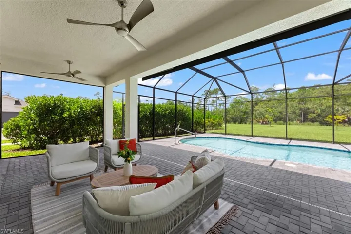 View of pool featuring a patio, an outdoor hangout area, ceiling fan, and enclosure