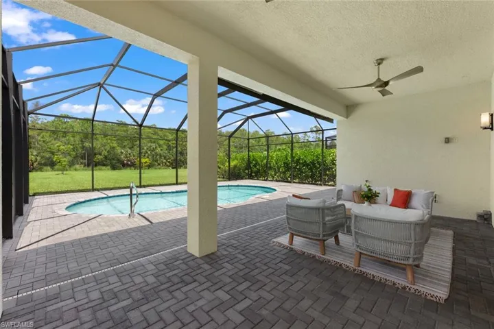 View of swimming pool featuring a lanai, a patio area, an outdoor living space, and ceiling fan