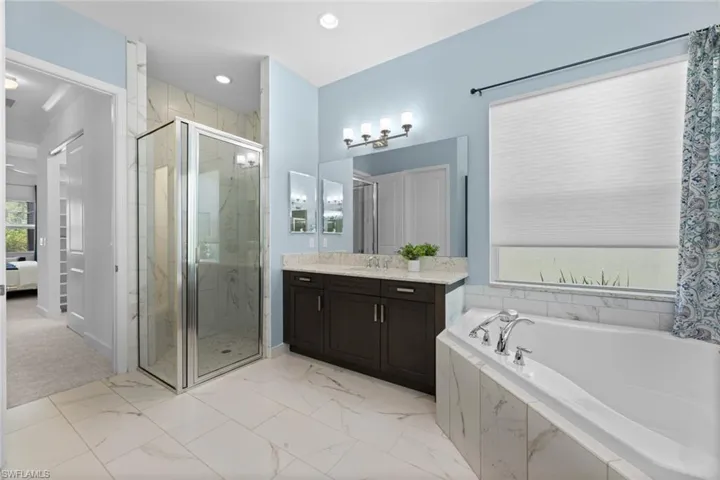 Bathroom with tile patterned flooring, shower with separate bathtub, and vanity