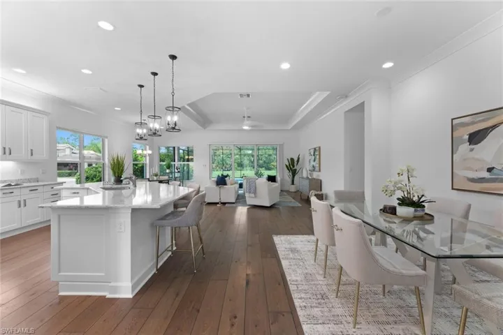 Kitchen featuring a breakfast bar area, white cabinets, dark wood- flooring, a center island, and a raised ceiling