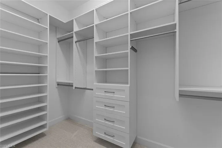 Spacious custom closet with light carpet