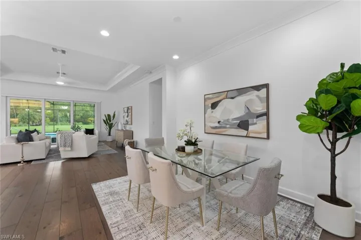 Dining area with dark hardwood / wood-style flooring, a raised ceiling, and ornamental molding