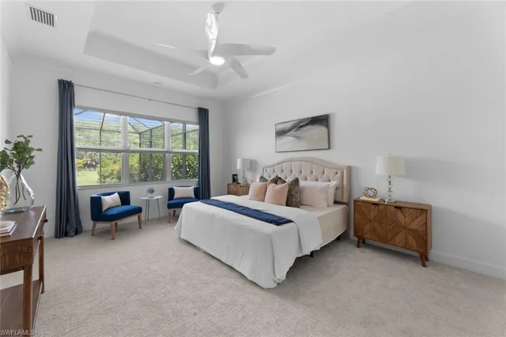 Newly Carpeted primary bedroom featuring ceiling fan and a tray ceiling