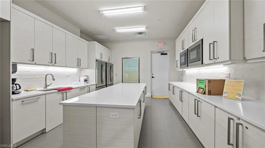 Community Catering Kitchen featuring tile patterned flooring, backsplash, a center island, stainless steel fridge, and sink