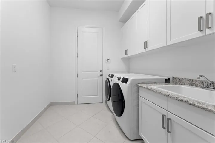Washroom with cabinets, separate washer and dryer, sink, and light tile patterned floors