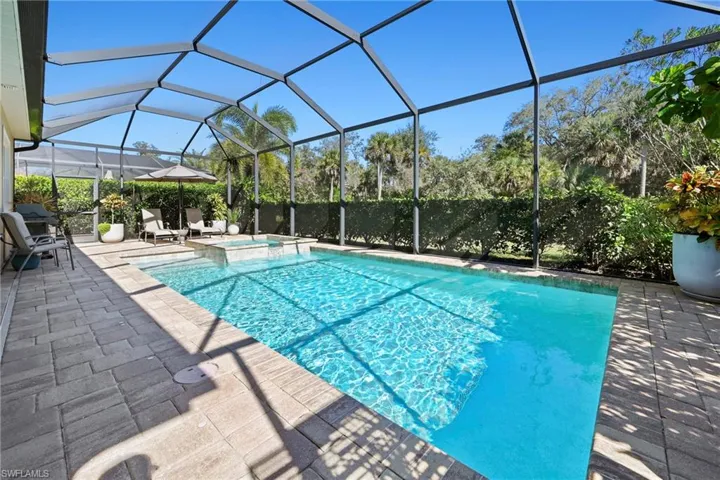 View of pool with glass enclosure, a sunroom, a pool with connected hot tub, and a patio area