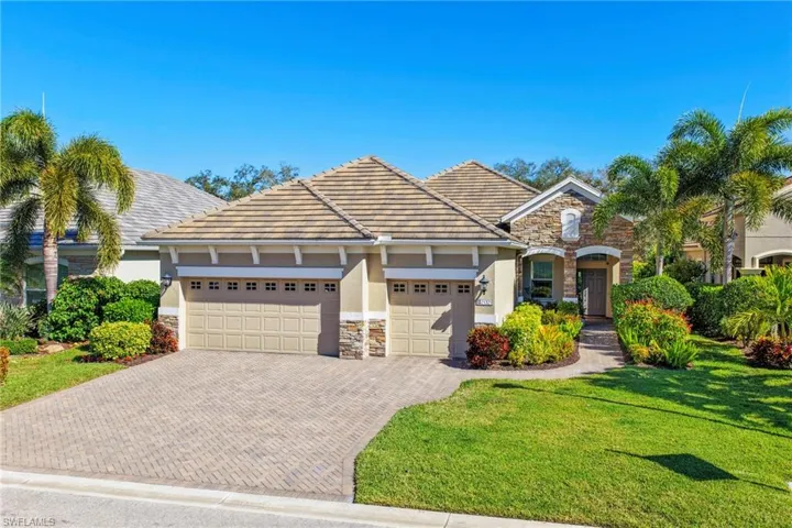 View of front facade with stone siding, a front lawn, decorative driveway, and a garage