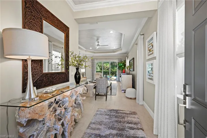 Foyer with a tray ceiling, ornamental molding, recessed lighting, and ceiling fan