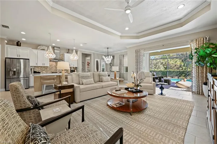 Living room featuring ornamental molding, a tray ceiling, a ceiling fan, recessed lighting, and a sunroom
