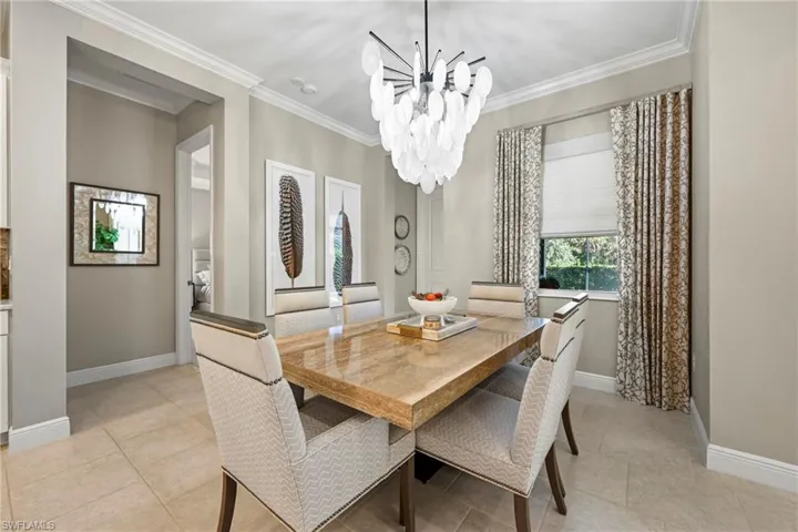 Dining area featuring ornamental molding, a chandelier, and light tile patterned floors