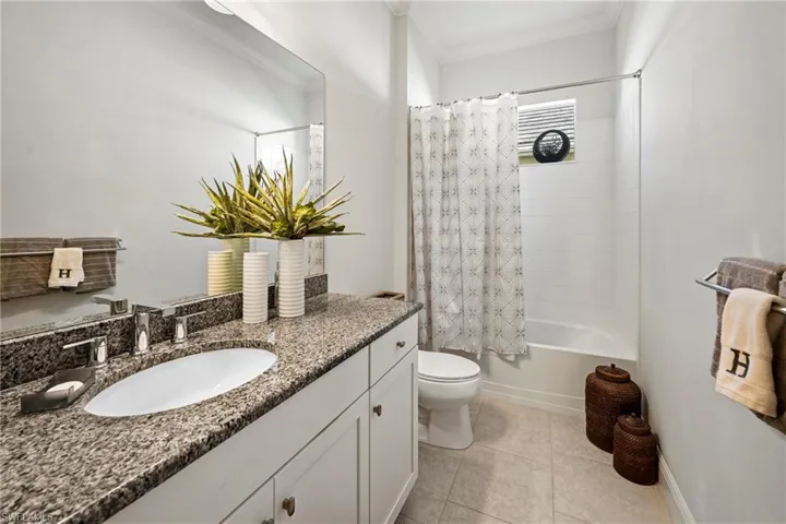 Bathroom with shower / bathtub combination with curtain, vanity, ornamental molding, and light tile patterned floors