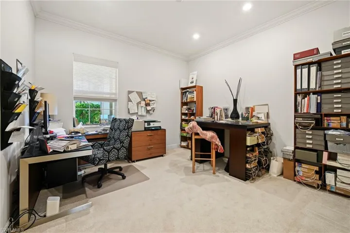 Bedroom currently used as an office space featuring light colored carpet and crown molding