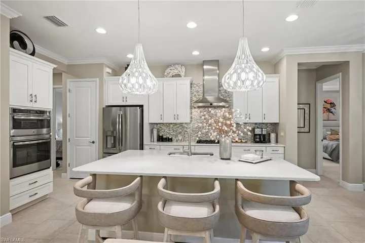Kitchen with crown molding, white cabinets, appliances with stainless steel finishes, decorative backsplash, and recessed lighting