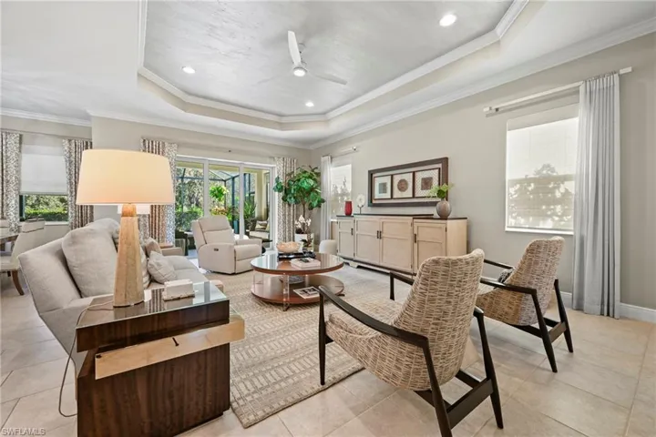 Living room with ceiling fan, healthy amount of natural light, ornamental molding, recessed lighting, and a tray ceiling