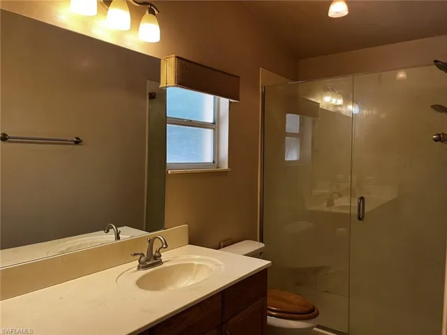 Bathroom with double sink vanity, toilet, and a shower.