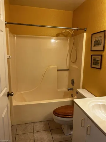 Full guest bathroom featuring vanity, toilet, tile patterned floors, and  shower/tub combination.