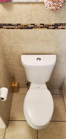 Bathroom featuring tile walls, tile patterned flooring, and toilet