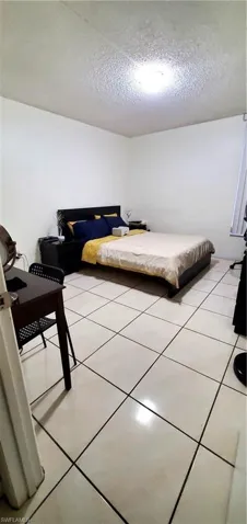 Bedroom with light tile patterned floors and a textured ceiling