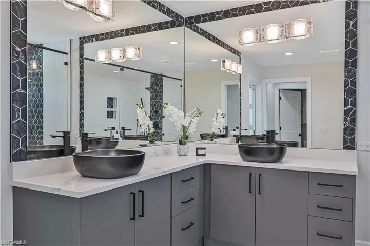 Full bath featuring double vanity, a tile shower, and recessed lighting