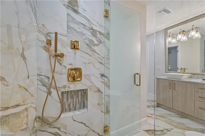 Bathroom with marble tiled floors, vanity, and a marble finish shower