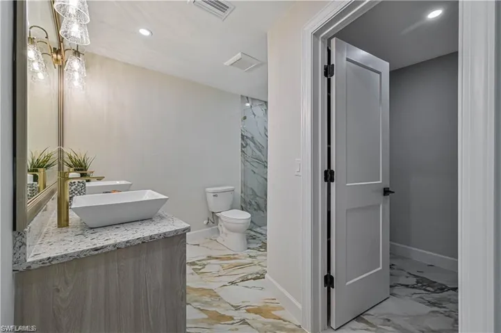 Full bath featuring marble tiled flooring, vanity, and recessed lighting