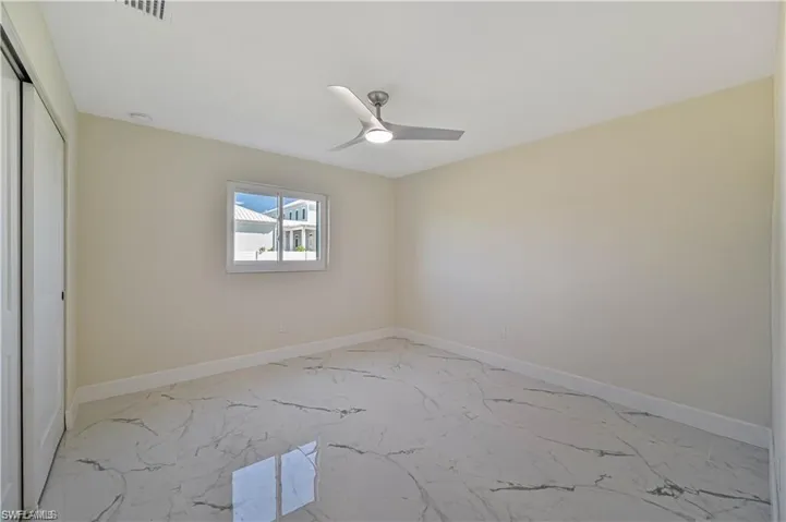 Unfurnished room with light marble finish floors and a ceiling fan