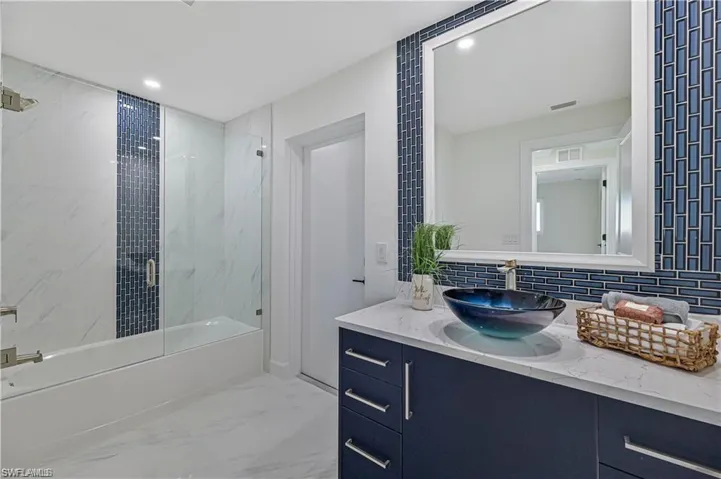 Full bath featuring vanity, marble finish floors, bath / shower combo with glass door, backsplash, and recessed lighting