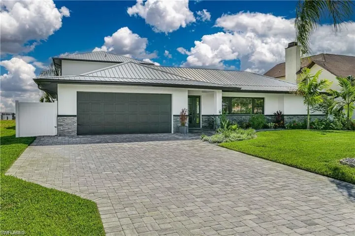 View of front facade featuring stone siding, a garage, stucco siding, and a front yard