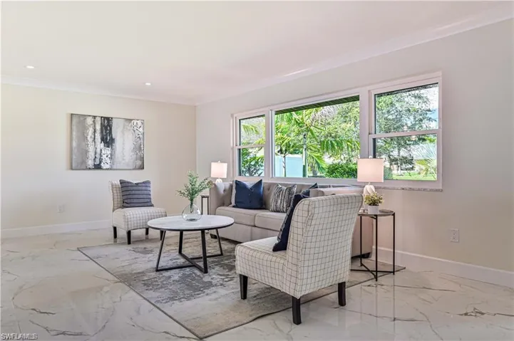 Living room with marble finish flooring, crown molding, and recessed lighting