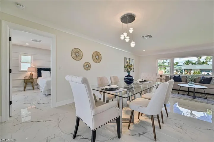 Dining room featuring plenty of natural light, light marble finish floors, and crown molding