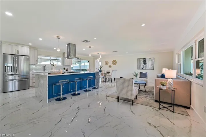 Kitchen featuring stainless steel fridge with ice dispenser, island range hood, modern cabinets, light countertops, and a kitchen island