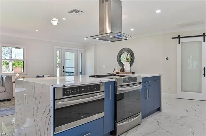 Kitchen featuring stainless steel appliances, island range hood, blue cabinets, modern cabinets, and recessed lighting