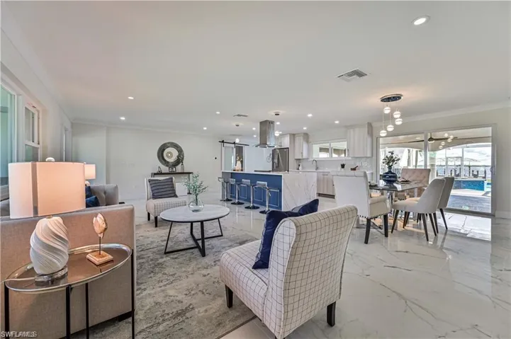 Living room with ornamental molding, recessed lighting, and light marble finish floors