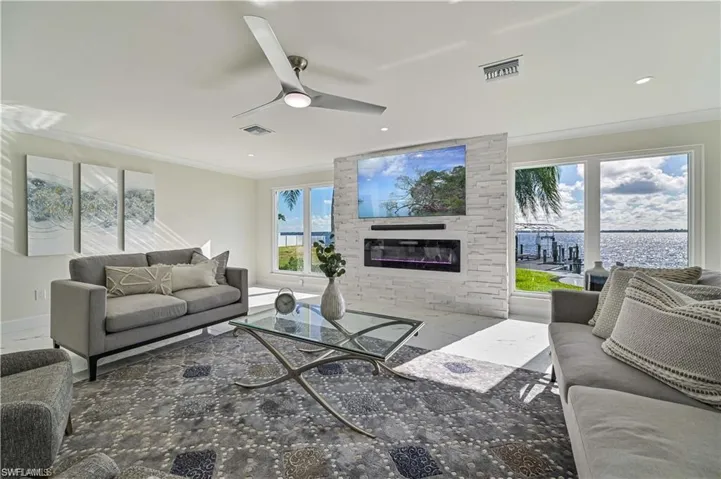 Living room with ornamental molding, plenty of natural light, a fireplace, a ceiling fan, and recessed lighting
