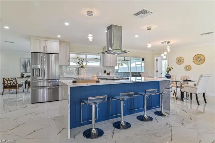 Kitchen featuring stainless steel fridge with ice dispenser, island exhaust hood, modern cabinets, a spacious island, and crown molding