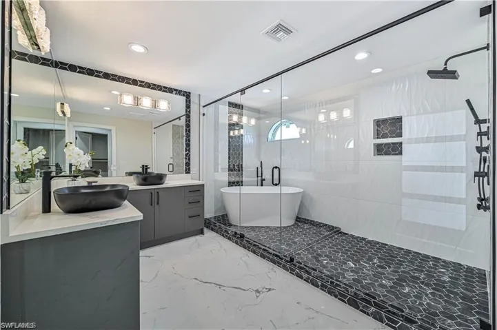 Full bath featuring a shower stall, double vanity, a soaking tub, recessed lighting, and marble tiled flooring
