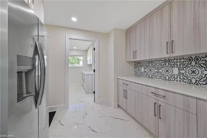 Kitchen featuring stainless steel fridge, light brown cabinetry, modern cabinets, decorative backsplash, and recessed lighting