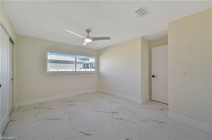Empty room featuring light marble finish floors and a ceiling fan